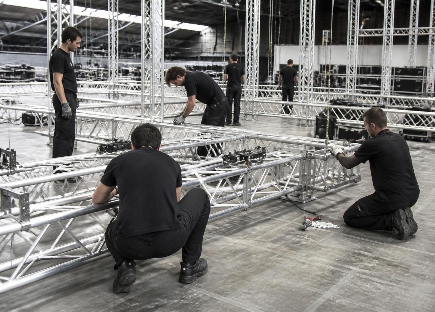 Equipo técnico ensamblando estructura de truss de aluminio para un escenario
